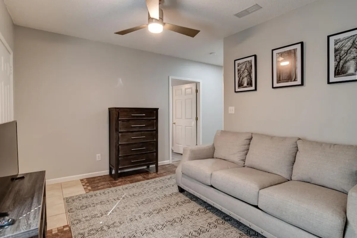A spacious living room with a comfortable sofa, dresser, and wall art. The atmosphere is inviting, ideal for socializing, relaxing after a day out, or enjoying a family movie night together.